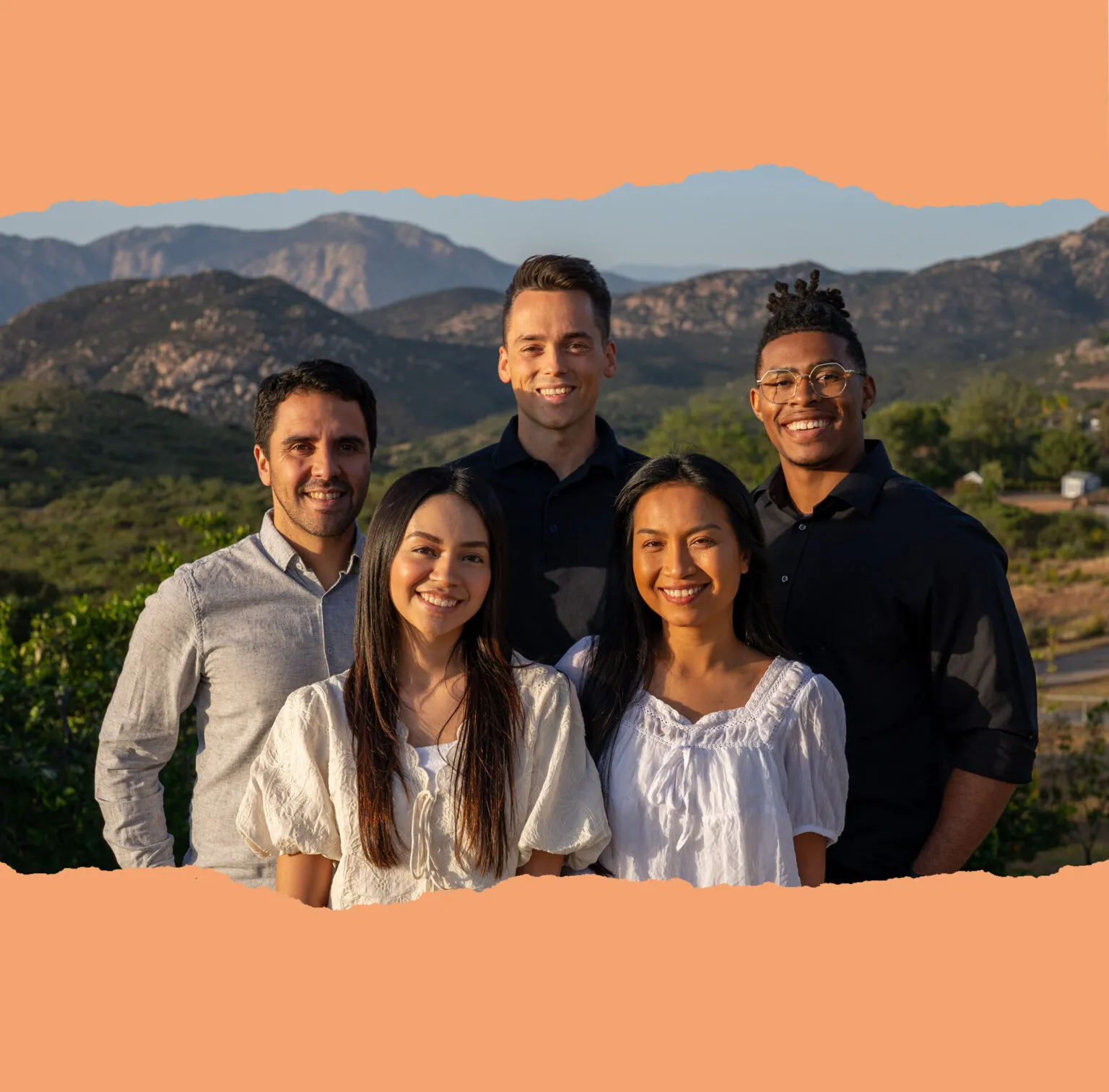 The Gems of Truth team smiling together in front of the Southern California mountains at golden hour