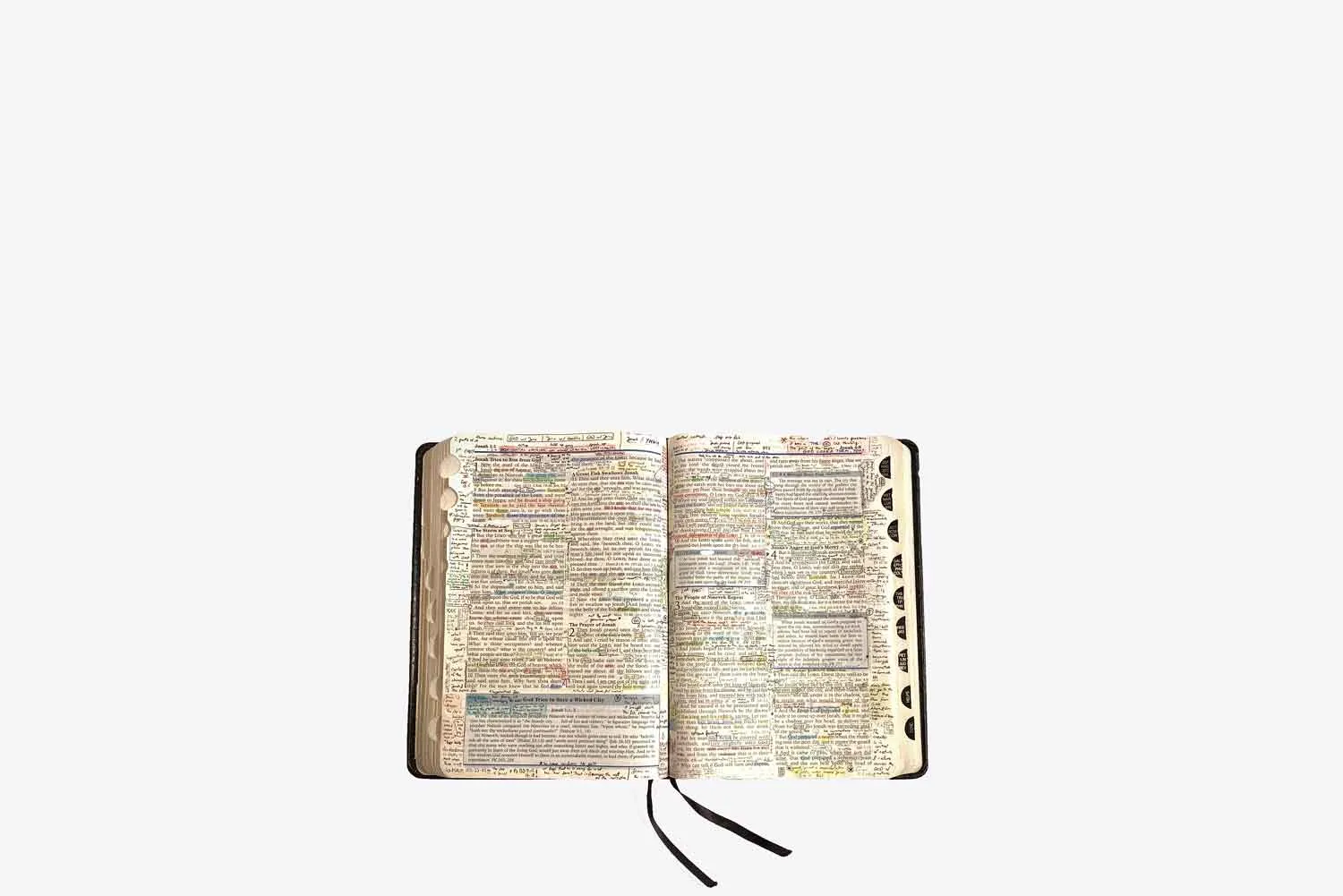 An open, well-read Bible with handwritten notes and ribbon markers